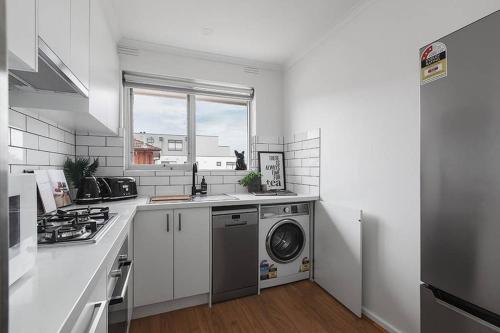 a kitchen with a washing machine and a window at Heart of Ormond Apartment by Ready Set Host in Carnegie