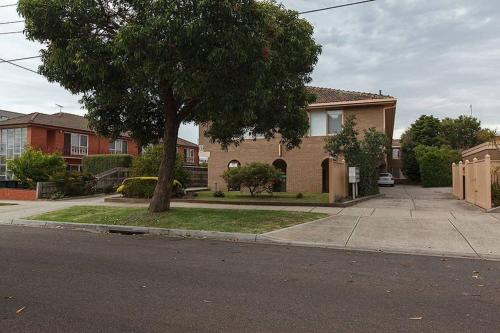 a house with a tree on the side of a street at Heart of Ormond Apartment by Ready Set Host in Carnegie