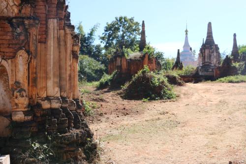 a dirt road next to a building with temples in the background at Sanctum Inle Resort in Nyaung Shwe
