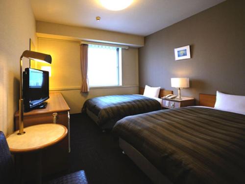 Route Inn Grantia Fukuyama Spa Resort في فوكوياما: غرفه فندقيه سريرين وتلفزيون