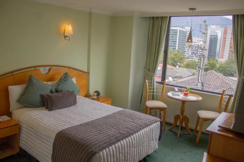 a hotel room with a bed and a view of a city at Hostal de La Mancha in Quito