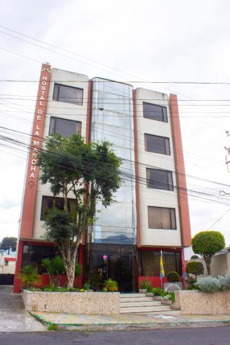 a large building with trees in front of it at Hostal de La Mancha in Quito