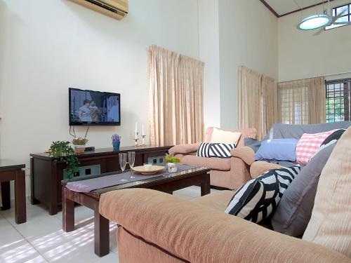 a living room with two couches and a tv at Melaka Afamosa Villa with Private Pool for 10 pax in Kampong Alor Gajah