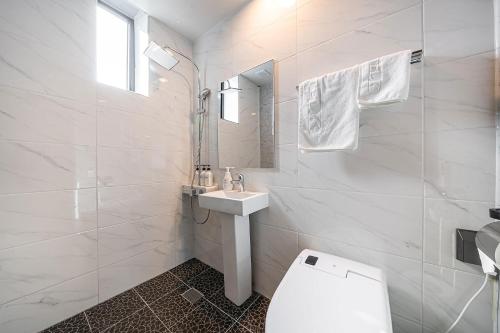 a white bathroom with a toilet and a sink at Hotel DDK in Seoul