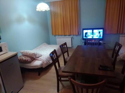 uma sala de jantar com uma mesa, uma cama e uma televisão em Borovets Apartments, Iglika 2 em Borovets