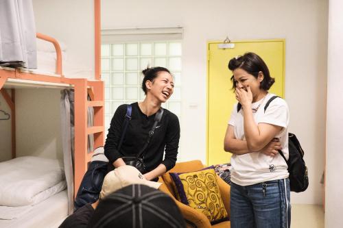 two women standing in a room with a bed at TG Hostel - stay together in Taichung