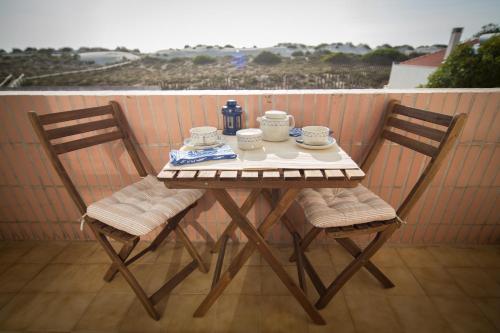 a table with two chairs and a tea set on a balcony at Barra Beach House - Praia da Barra in Praia da Barra