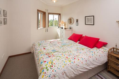 a bedroom with a large bed with red pillows at Barra Beach House - Praia da Barra in Praia da Barra