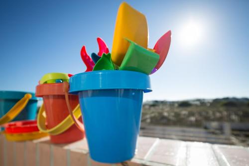 una taza de plástico azul llena de plumas de diferentes colores en Barra Beach House - Praia da Barra, en Praia da Barra