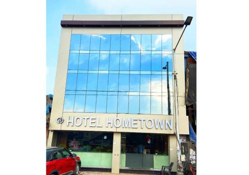 Hotel Hometown Near US Embassy BKC في مومباي: مبنى هرمونات الفندق مع سيارة حمراء متوقفة في الأمام