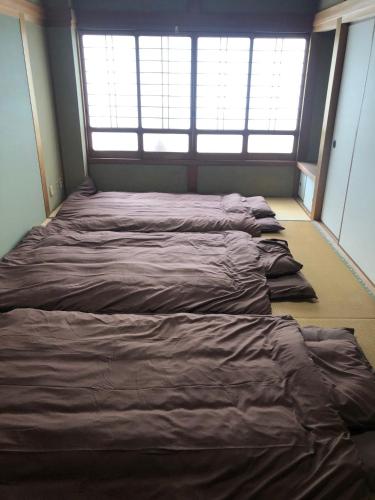 a row of beds in a room with windows at 浜の宮七福神 1棟貸し9名様までご利用できます in Nachikatsuura