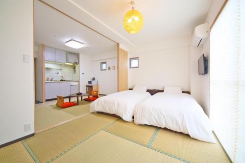a bedroom with two beds and a kitchen at Apartment HOTEL KIRO Kyoto STATION in Kyoto