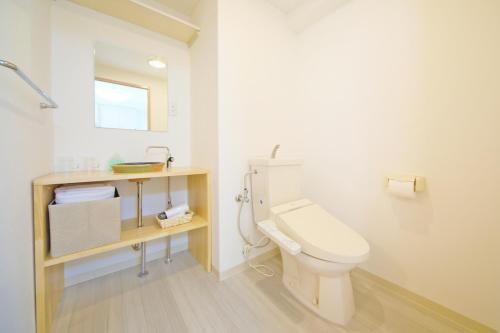 a white bathroom with a toilet and a sink at Apartment HOTEL KIRO Kyoto STATION in Kyoto