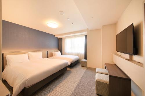 Habitación de hotel con 2 camas y TV de pantalla plana. en Richmond Hotel Yokohama Ekimae, en Yokohama