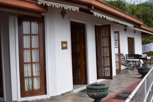a white house with wooden doors and a patio at The Mist Holiday Bungalow in Haputale