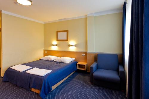 ein Hotelzimmer mit einem Bett und einem blauen Stuhl in der Unterkunft Dom Sportowca Błonie - MOSiR in Sanok