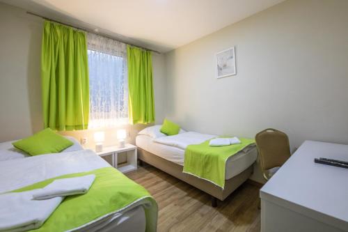 a room with two beds and a window with green curtains at Hotel Slovan in Lučenec