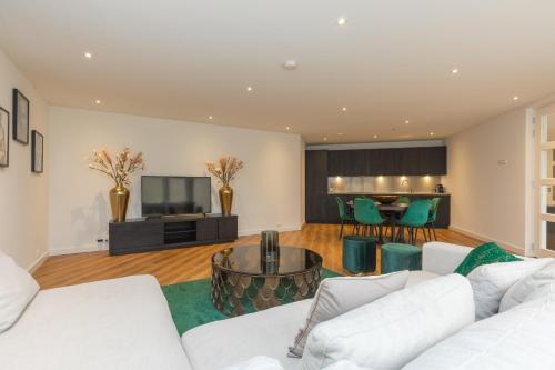 a living room with white couches and a television at Lage Wurft Beach Apartments in Noordwijk