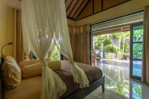 a bedroom with a canopy bed with a large window at Villa Latebra in Lovina