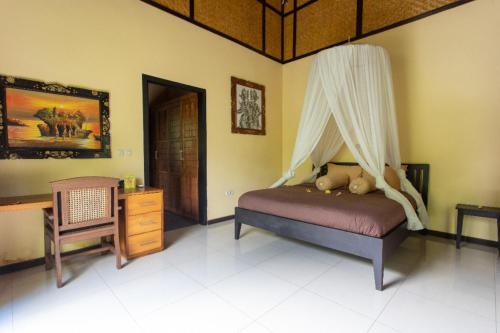 a bedroom with a bed with a canopy and a desk at Villa Latebra in Lovina