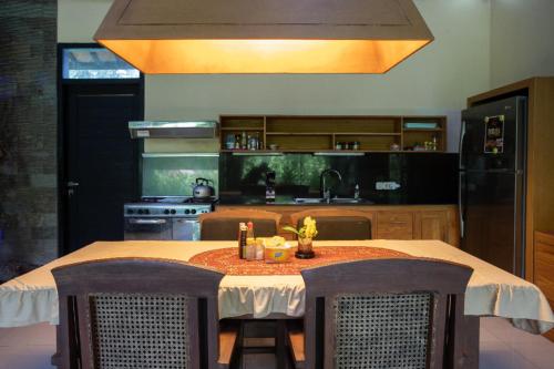 a kitchen with a table with chairs and a kitchen with a refrigerator at Villa Latebra in Lovina