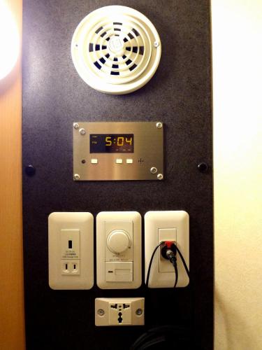 a clock on the wall of a room with a light and an alarm at Guesthouse kukuru in Wakayama