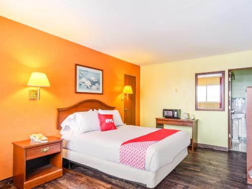 - une chambre avec un grand lit et des murs orange dans l'établissement OYO Hotel Downtown Peoria I-74, à Peoria