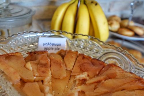 a pie on a glass plate with bananas in the background at Livadi Suites in Arachova