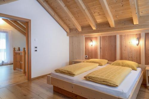 sypialnia z 2 łóżkami w pokoju z drewnianymi ścianami w obiekcie Apartment Dolomiten w mieście San Martino in Badia
