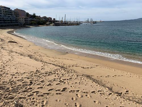 a beach with footprints in the sand and the water at T3 vue mer in Propriano