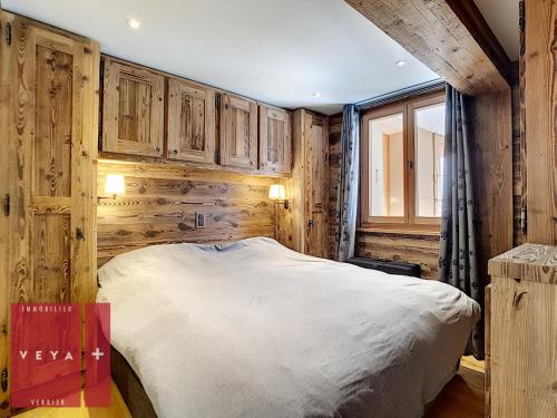 - une chambre avec des murs en bois et un grand lit dans l'établissement Erika 012, à Verbier