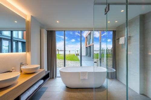 a bathroom with two sinks and a tub at Postillion Amersfoort Veluwemeer in Putten