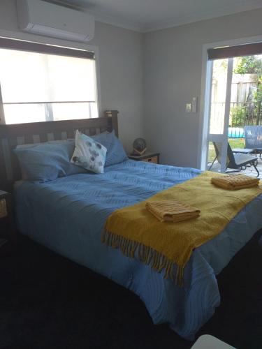 a bedroom with a blue bed with a yellow blanket at Sleepout Hideaway in Rotorua