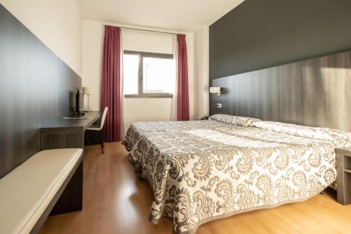 1 dormitorio con cama, escritorio y ventana en Hotel Abades Via Norte en Miranda de Ebro