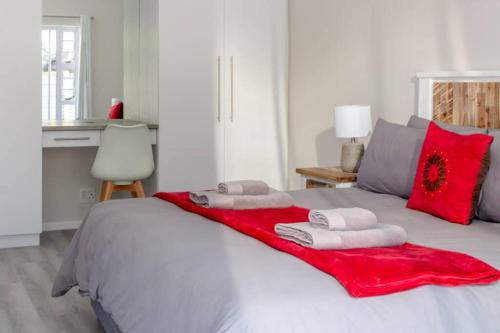 Cama blanca con almohadas rojas y manta roja en 10 on Aquavista Addo River View Villa en Colchester