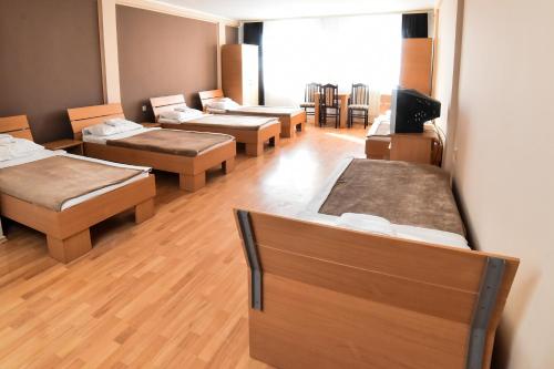 a row of beds in a room with wooden floors at Hostel Milkaza in Novi Sad