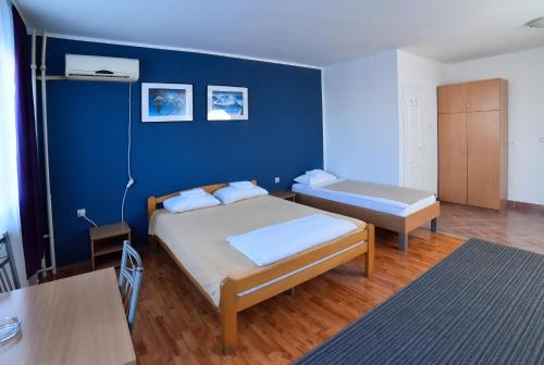 1 dormitorio con 2 camas y pared azul en Hostel Milkaza, en Novi Sad