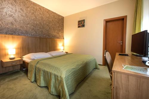 a hotel room with a bed and a desk and a computer at Hotel Slovan in Lučenec