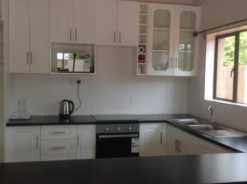 a kitchen with white cabinets and a black counter top at 848 Guest House in Victoria Falls