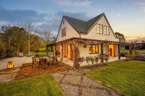 a house with a table and chairs in the yard at The Last Straw Cottage Nelson in Brightwater