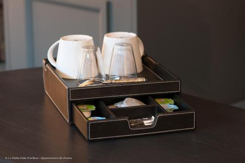 une boîte noire avec des tasses et des tasses sur une table dans l'établissement La Petite Folie, à Honfleur