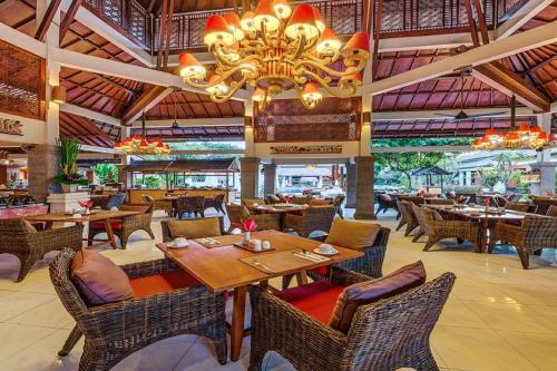 クタにあるラマ ビーチ リゾート アンド ヴィラスのテーブルと椅子、シャンデリアのあるレストラン