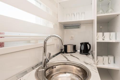 a kitchen with a sink in a white kitchen at Pool Apartments & Rooms Mare in Novalja