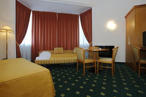 a hotel room with a bed and a table and a couch at Hotel Estense in Modena