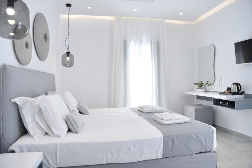 a white bedroom with a bed with white sheets and pillows at Crystal Mare Suites in Naxos Chora