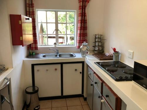 uma cozinha com um lavatório, um fogão e uma janela em Peace Corner Cottages em Dullstroom