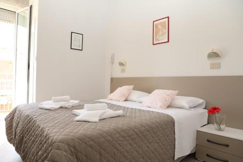 um quarto com uma cama grande com almofadas cor-de-rosa e brancas em Hotel A Casa Nostra em Rimini