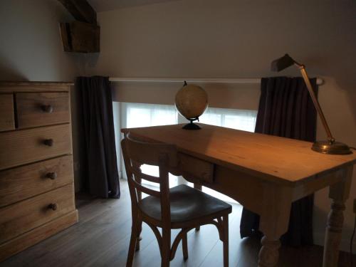 a wooden desk with a lamp and a chair at LA PETITE ECOLE in Chambellay