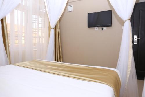 a bedroom with a bed with white curtains and a tv at Anchor Hotel in Nairobi