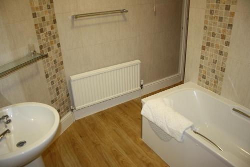 a bathroom with a white tub and a sink at The White Lion Inn in Oakham
